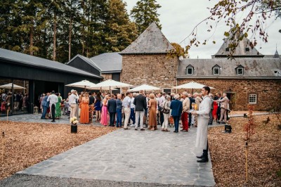 Bâtiment moderne en bois noir avec toit en pente, entouré d'arbres et d'un sol couvert de feuilles d'automne.