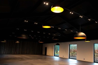 Bâtiment moderne en bois noir avec toit en pente, entouré d'arbres et d'un sol couvert de feuilles d'automne.