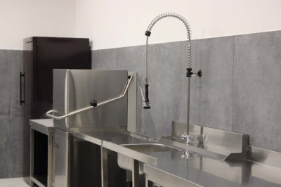 Bâtiment moderne en bois noir avec toit en pente, entouré d'arbres et d'un sol couvert de feuilles d'automne.