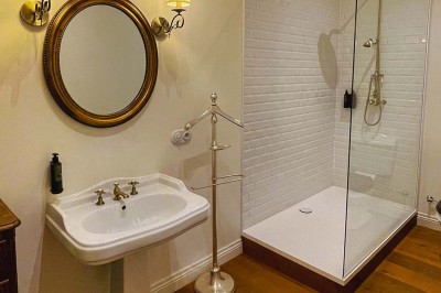 Bâtiment moderne en bois noir avec toit en pente, entouré d'arbres et d'un sol couvert de feuilles d'automne.