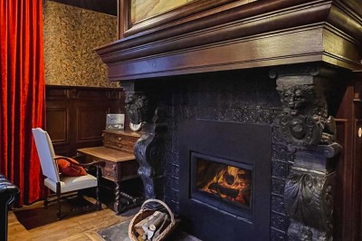 Bâtiment moderne en bois noir avec toit en pente, entouré d'arbres et d'un sol couvert de feuilles d'automne.