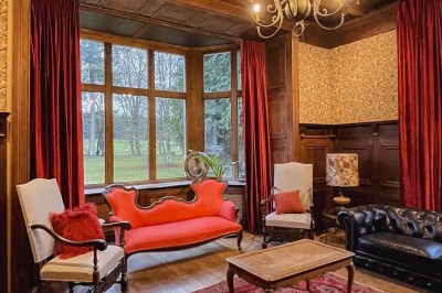 Bâtiment moderne en bois noir avec toit en pente, entouré d'arbres et d'un sol couvert de feuilles d'automne.