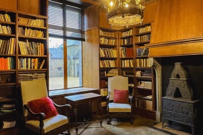 Bâtiment moderne en bois noir avec toit en pente, entouré d'arbres et d'un sol couvert de feuilles d'automne.