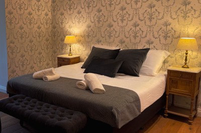 Bâtiment moderne en bois noir avec toit en pente, entouré d'arbres et d'un sol couvert de feuilles d'automne.