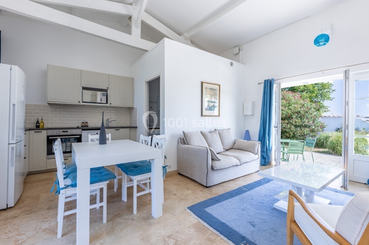 Intérieur lumineux avec cuisine ouverte, table à manger, salon et accès à une terrasse donnant sur un jardin.