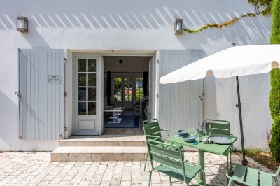 Vieille brouette en bois devant un mur en pierre et une porte en bois usée, sous un ciel dégagé.