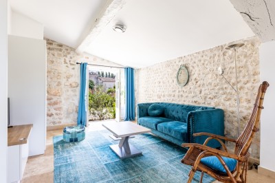 Vieille brouette en bois devant un mur en pierre et une porte en bois usée, sous un ciel dégagé.