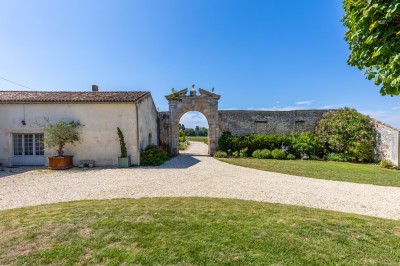 Vieille brouette en bois devant un mur en pierre et une porte en bois usée, sous un ciel dégagé.