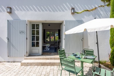 Vieille brouette en bois devant un mur en pierre et une porte en bois usée, sous un ciel dégagé.