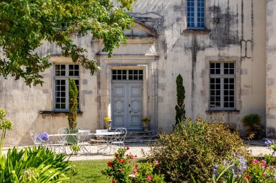 Vieille brouette en bois devant un mur en pierre et une porte en bois usée, sous un ciel dégagé.