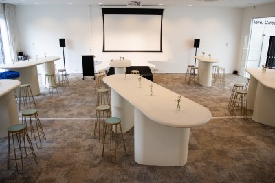 Miniature Grande salle - Format Soirée ( mobilier non fourni) Salle de réunion lumineuse avec une table blanche, des chaises grises, un écran mural et un tableau de présentation.