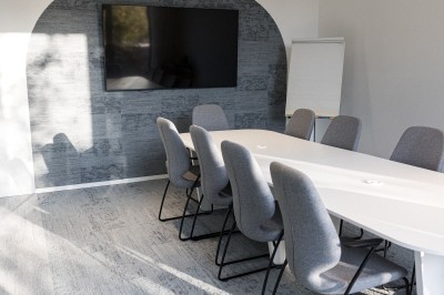 Miniature Salle de réunion - Compose Salle de réunion lumineuse avec une table blanche, des chaises grises, un écran mural et un tableau de présentation.
