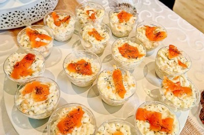 Groupe de personnes réunies dans une salle lumineuse autour d'un buffet varié avec boissons et plats.