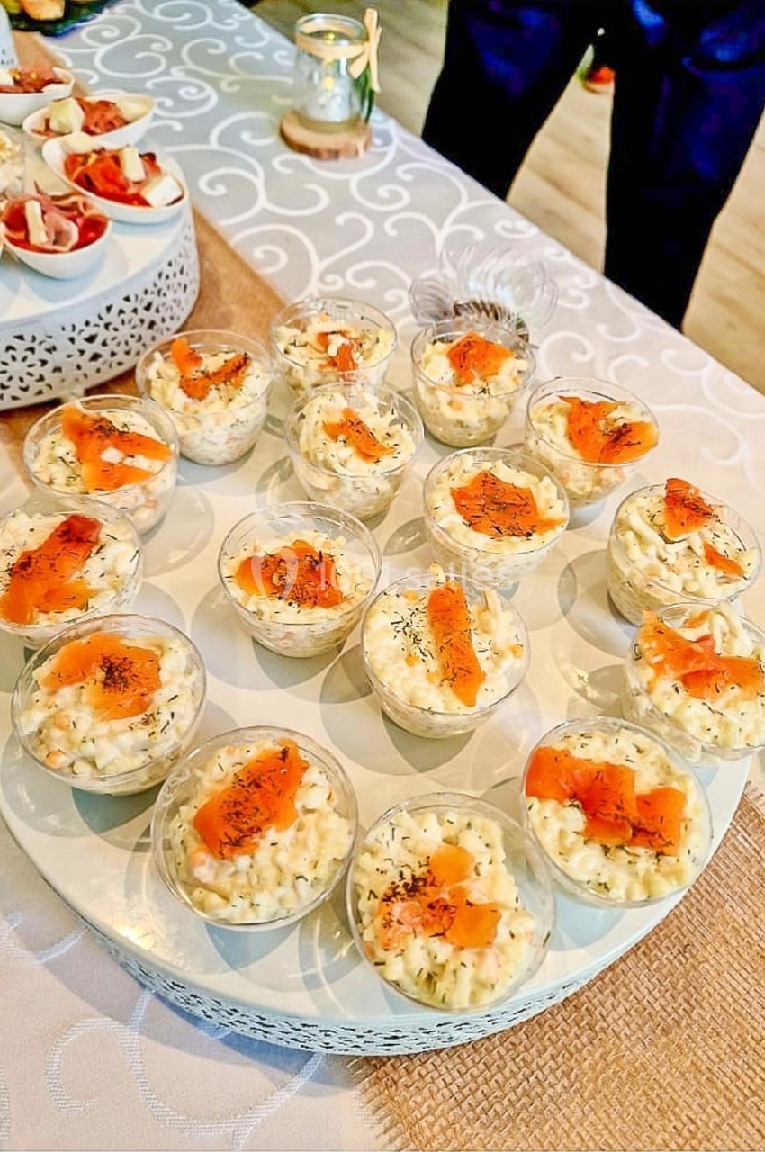 Plateau de verrines de riz crémeux garnies de saumon fumé et d'aneth, présenté sur une nappe claire.