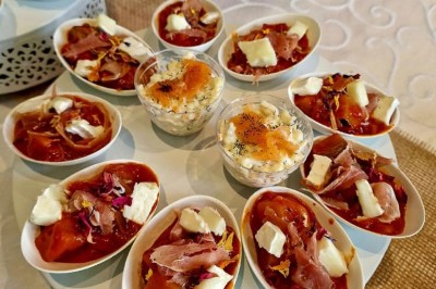 Groupe de personnes réunies dans une salle lumineuse autour d'un buffet varié avec boissons et plats.