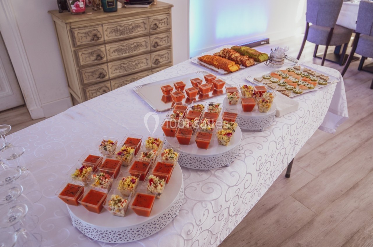 Buffet avec verrines colorées, toasts et amuse-bouches disposés sur une table recouverte d'une nappe blanche.