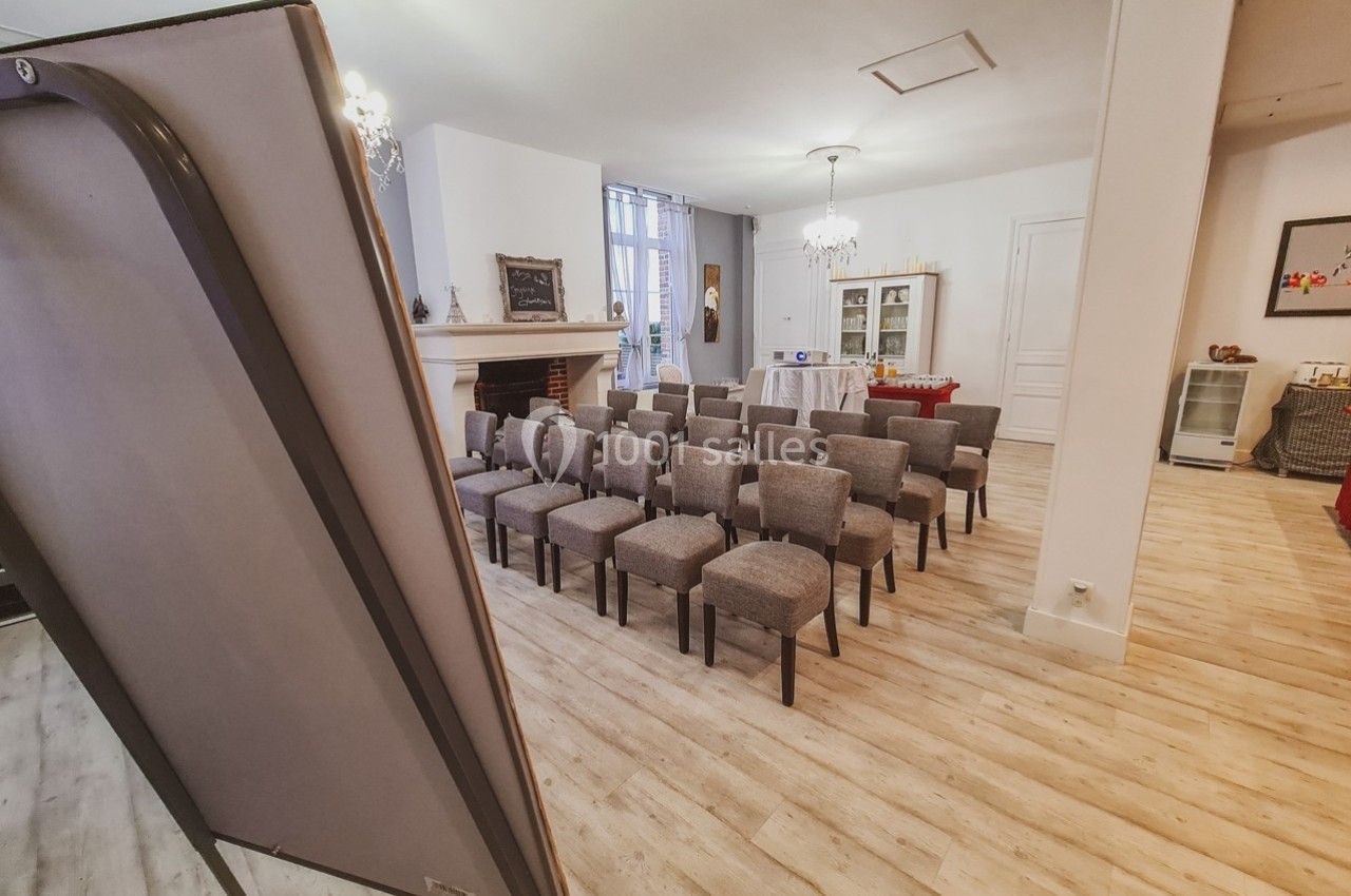 Salle lumineuse aménagée avec des chaises alignées face à un tableau, prête pour une réunion ou une présentation.