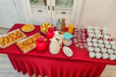 Groupe de personnes réunies dans une salle lumineuse autour d'un buffet varié avec boissons et plats.