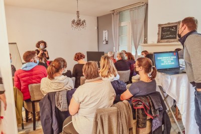 Groupe de personnes réunies dans une salle lumineuse autour d'un buffet varié avec boissons et plats.