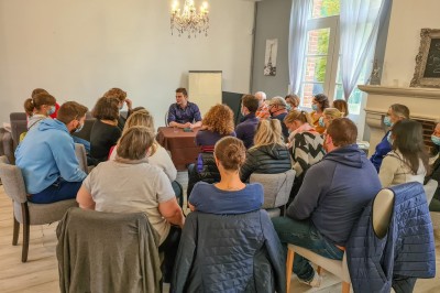 Groupe de personnes réunies dans une salle lumineuse autour d'un buffet varié avec boissons et plats.