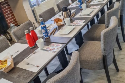 Groupe de personnes réunies dans une salle lumineuse autour d'un buffet varié avec boissons et plats.