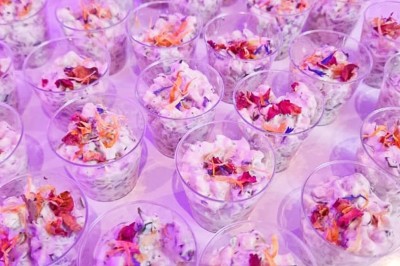 Groupe de personnes réunies dans une salle lumineuse autour d'un buffet varié avec boissons et plats.