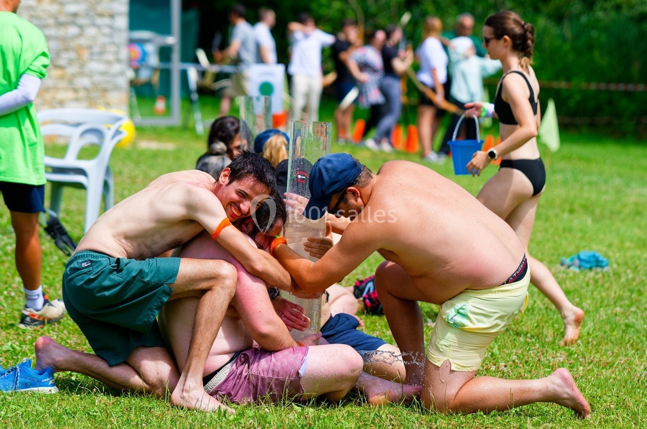 Des personnes participent à une activité ludique en extérieur, manipulant un grand tube transparent sur une pelouse.