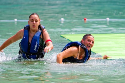 Voilier blanc amarré sur un lac calme, entouré de montagnes verdoyantes sous un ciel dégagé.