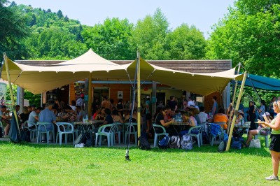 Voilier blanc amarré sur un lac calme, entouré de montagnes verdoyantes sous un ciel dégagé.
