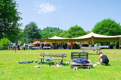 Voilier blanc amarré sur un lac calme, entouré de montagnes verdoyantes sous un ciel dégagé.