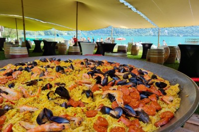 Voilier blanc amarré sur un lac calme, entouré de montagnes verdoyantes sous un ciel dégagé.