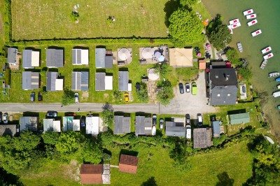 Voilier blanc amarré sur un lac calme, entouré de montagnes verdoyantes sous un ciel dégagé.
