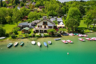 Voilier blanc amarré sur un lac calme, entouré de montagnes verdoyantes sous un ciel dégagé.