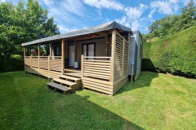 Voilier blanc amarré sur un lac calme, entouré de montagnes verdoyantes sous un ciel dégagé.