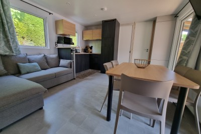 Voilier blanc amarré sur un lac calme, entouré de montagnes verdoyantes sous un ciel dégagé.