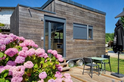 Voilier blanc amarré sur un lac calme, entouré de montagnes verdoyantes sous un ciel dégagé.