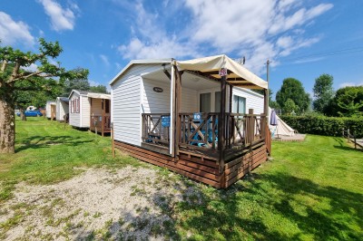 Voilier blanc amarré sur un lac calme, entouré de montagnes verdoyantes sous un ciel dégagé.