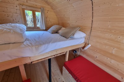 Voilier blanc amarré sur un lac calme, entouré de montagnes verdoyantes sous un ciel dégagé.