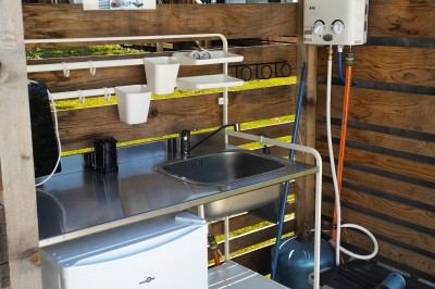 Voilier blanc amarré sur un lac calme, entouré de montagnes verdoyantes sous un ciel dégagé.