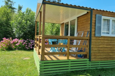 Voilier blanc amarré sur un lac calme, entouré de montagnes verdoyantes sous un ciel dégagé.