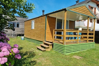Voilier blanc amarré sur un lac calme, entouré de montagnes verdoyantes sous un ciel dégagé.