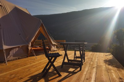 Voilier blanc amarré sur un lac calme, entouré de montagnes verdoyantes sous un ciel dégagé.