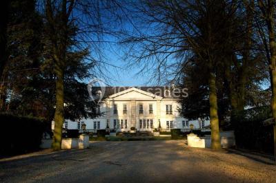 Lustre en cristal allumé suspendu au-dessus d'un escalier avec rampe en fer forgé et sol en marbre.