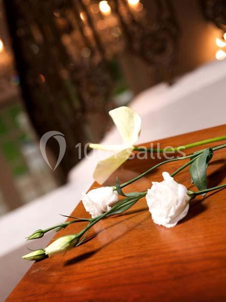 Fleurs blanches posées sur une table en bois, avec un arrière-plan flou de lumières et de décorations.