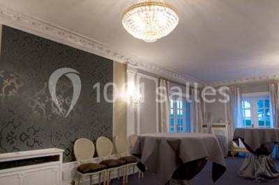 Lustre en cristal allumé suspendu au-dessus d'un escalier avec rampe en fer forgé et sol en marbre.