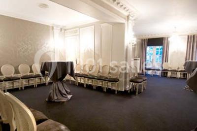 Lustre en cristal allumé suspendu au-dessus d'un escalier avec rampe en fer forgé et sol en marbre.