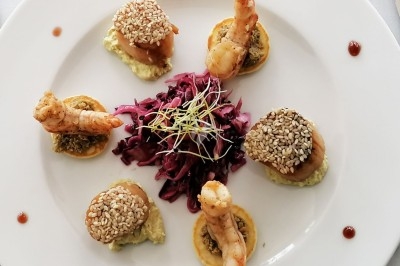 Plateau de fromages variés entourés de grappes de raisin, noix et herbes fraîches sur une table claire.