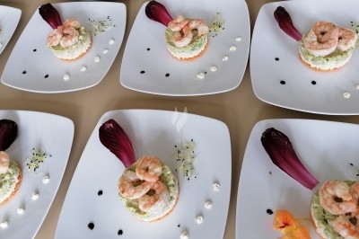 Filet de poisson avec sauce au vin rouge, purée, lard croustillant et garniture de champignons sur une assiette blanche.