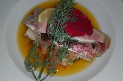 Filet de poisson avec sauce au vin rouge, purée, lard croustillant et garniture de champignons sur une assiette blanche.