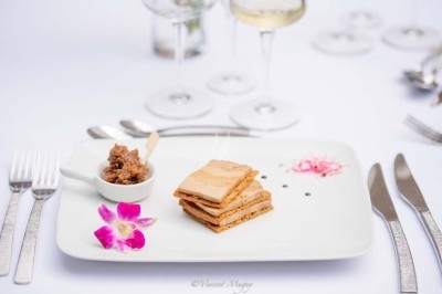 Plateau de fromages variés entourés de grappes de raisin, noix et herbes fraîches sur une table claire.